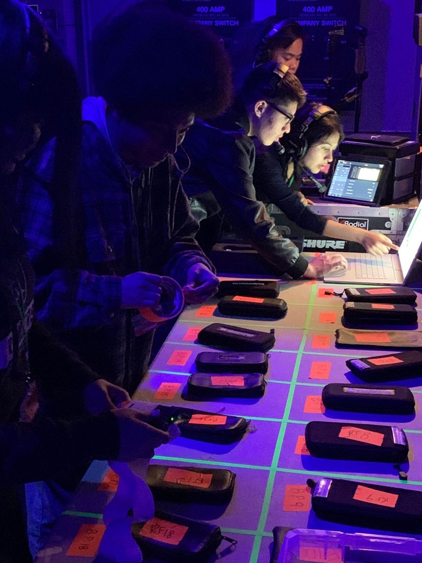 Crew checking out mic packs before a show